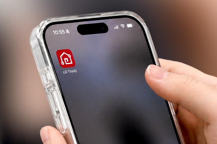 Una persona sosteniendo un teléfono inteligente con la aplicación LG ThinQ en la pantalla.