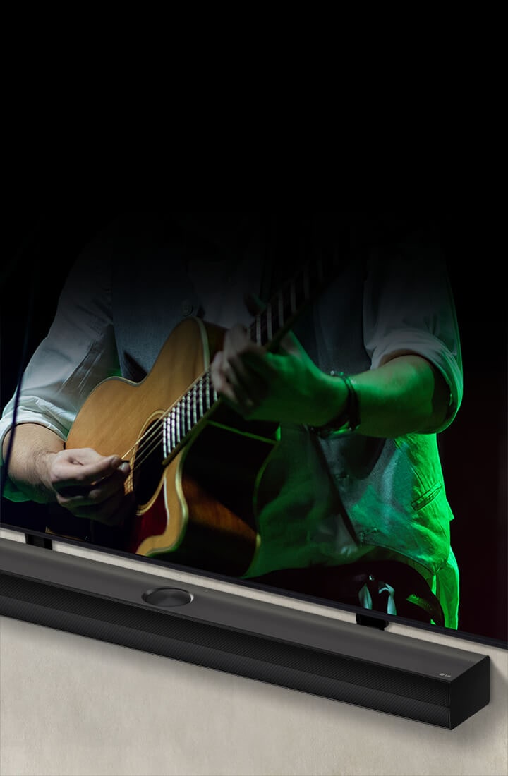 La barra de sonido LG sobre un fondo negro revela su diseño empezando por la esquina izquierda, y luego se aleja para mostrar toda la barra de sonido. Aparece un televisor LG QNED con Synergy Bracket. La barra de sonido se coloca encima del soporte Synergy Bracket, se presiona contra la pared y se ve la pantalla inferior del televisor, que muestra a un hombre tocando la guitarra.