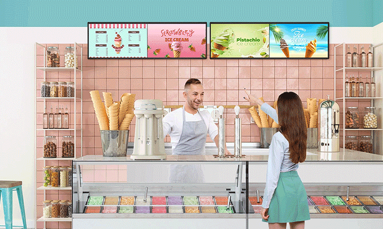 Aparece una BH7N instalada en el interior de una heladería, y en la pantalla se proyectan simultáneamente el menú del helado y anuncios publicitarios.