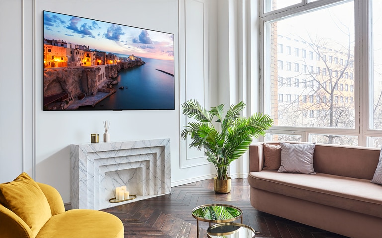 A screen showing the webOS 23 New Home UX pans to the right, and a landscape shot appears on the screen. The black background becomes a bright and modern living space with LG OLED hanging on the wall.