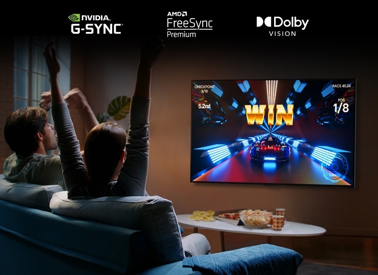 Dos personas sentadas en un sofá jugando un juego de carreras con un control y LG OLED G2 en una sala de estar.