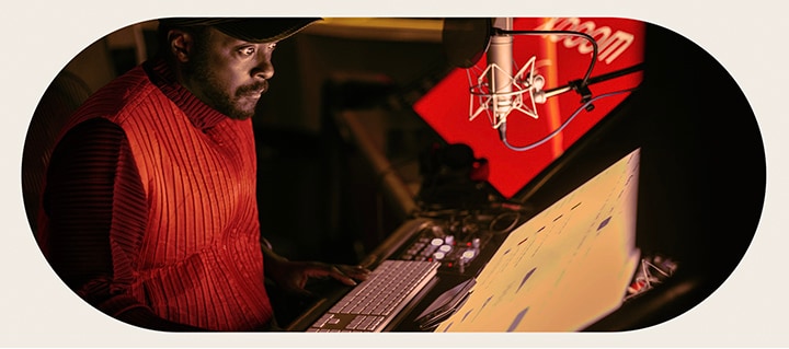 will.i.am está trabajando en el estudio, mirando una pantalla colocada debajo de un micrófono.