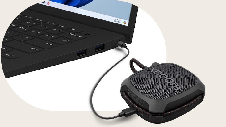 Un portátil LG gram conectado al parlante LG XBOOM Rock mediante cable USB-C, ilustrando reproducción de audio sin pérdida a través de conexión cableada.
