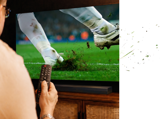 Ruka držící dálkové ovládání při sledování fotbalu v televizi