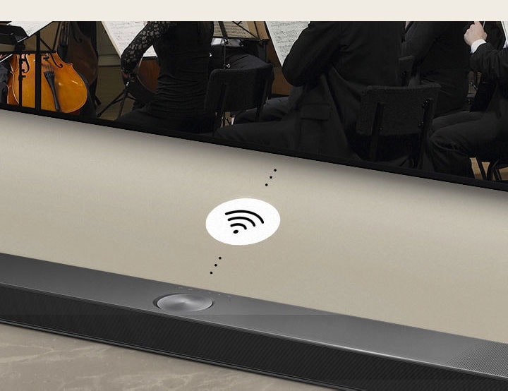 Detail soundbaru LG Soundbar pod LG TV. Mezi soundbarem LG Soundbar a LG TV je symbol konektivity, který znázorňuje bezdrátový provoz zařízení WOWCAST.