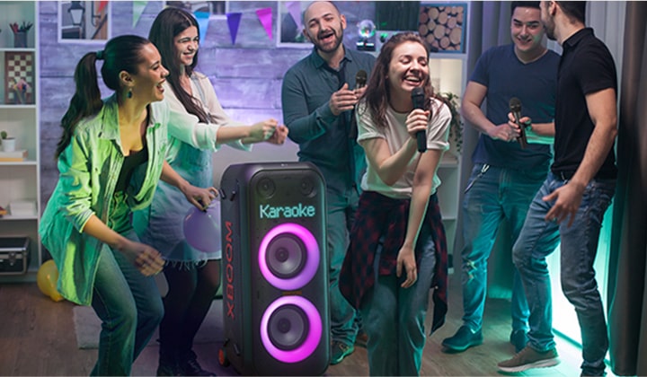 V obývacím pokoji si lidé užívají karaoke.