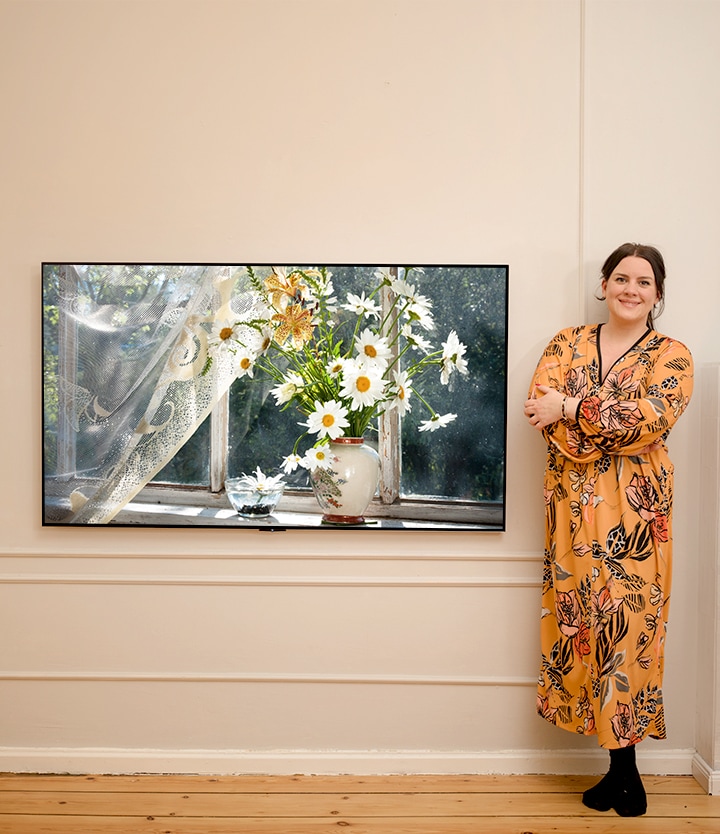 This is a video in which an image of a woman with a flower passing in front of a TV and an image of a woman next to a washing machine appear in succession.