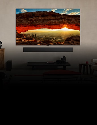 Wandmontierter OLED evo TV mit lebhaftem Sonnenuntergang durch den roten Felsbogen im modernen Wohnzimmer.
