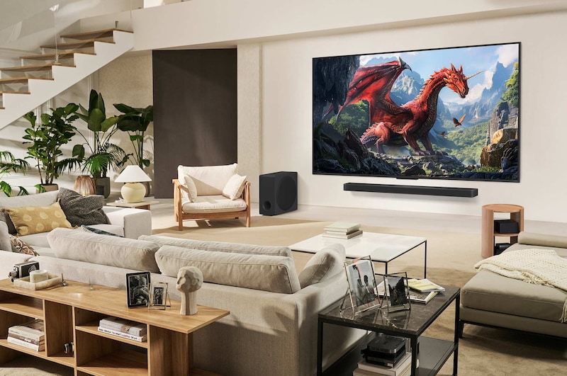 Eine Familie sitzt auf einer Couch vor einem LG QNED TV, der an der Wand über einer LG Soundbar befestigt ist. Die Zero Connect Box befindet sich in einem Couchtisch.