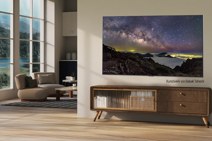 Innenraum eines Landhauses. Ein riesiger, an der Wand befestigter LG-Fernseher zeigt auf dem Bildschirm ein wunderschönes Landschaftsbild. Der Fernseher sieht aus wie ein Foto, das an der Wand hängt. 