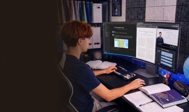 Ein Student sitzt am Schreibtisch und lernt mit Vorlesungsvideos und Lernmaterialien auf einem Curved-Monitor.