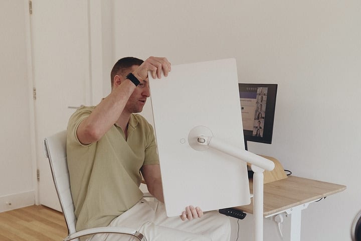 Ein Mann, der auf einem Stuhl sitzt und einen StanbyME 2 Smart Screen auf einen 90-Grad-Winkel dreht.