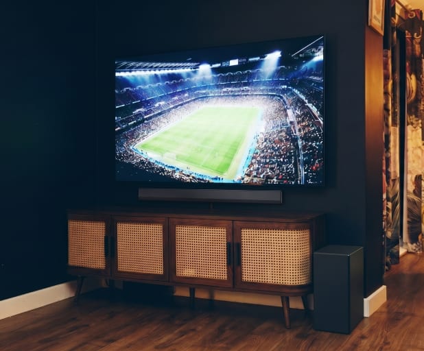 Nahaufnahme einer Soundbar unter einem Fernseher auf einem Holzschrank.