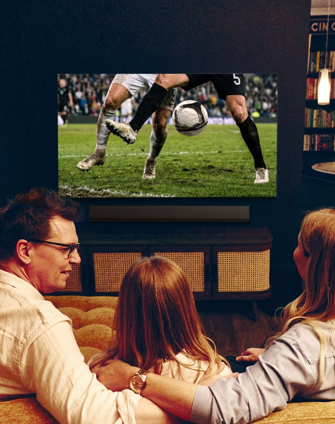 Familie sieht von hinten ein Fußballspiel im Fernsehen