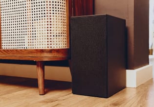 Kabelloser Subwoofer neben einem Holzschrank im Wohnzimmer