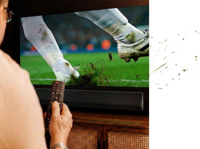 Hand hält eine Fernbedienung beim Ansehen eines Fußballspiels im Fernsehen