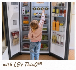 Ein Kleinkind greift in einen offenen, beleuchteten Kühlschrank. [mit LG ThinQ™]