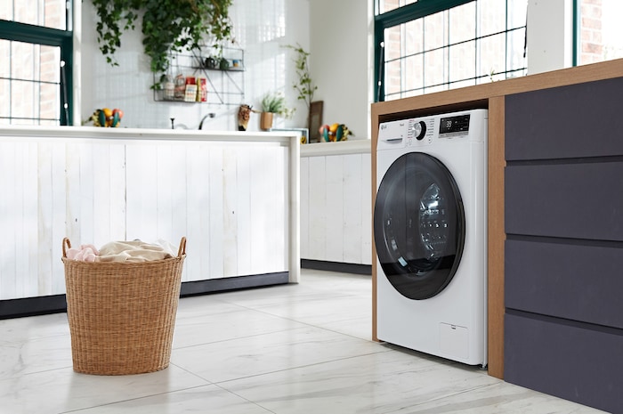 Die weiße LG 9 kg Slim-Waschmaschine F2V7SLIM9, mit ihrem platzsparenden Design in einem modernen Waschraum installiert, mit Energieeffizienzklasse A-10%.