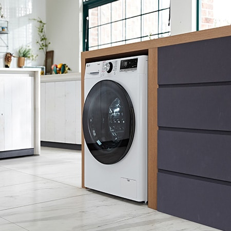 Die weiße LG 9 kg Slim-Waschmaschine F2V7SLIM9, mit ihrem platzsparenden Design in einem modernen Waschraum installiert, mit Energieeffizienzklasse A-10%.