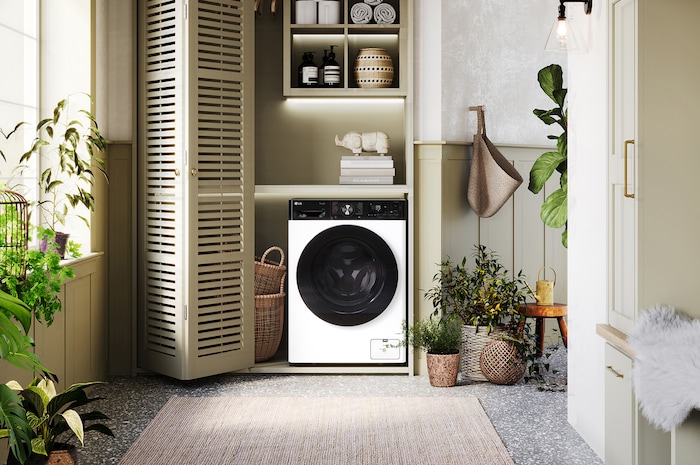 Die weiße LG 9 kg Waschmaschine F4WR709YP mit markantem schwarzem Bullaugenring, installiert in einem stilvollen, modernen Waschraum, mit Energieeffizienzklasse A-10%.