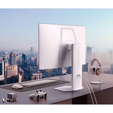 Weißer LG UltraGear 32-Zoll Gaming-Monitor auf modernem Schreibtisch mit Stadtblick, kombiniert mit Gaming- und Arbeitszubehör.