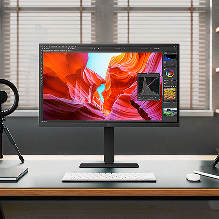 LG UltraFine 27-Zoll UHD 4K Monitor auf einem Holzschreibtisch, eingerichtet mit Kreativsoftware und Zubehör.