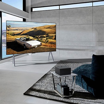 Zero Connect Box auf einem Tisch in einem luxuriösen Wohnzimmer streamt eine Orchesteraufführung auf den LG Signature OLED M4 True Wireless TV Fernseher.