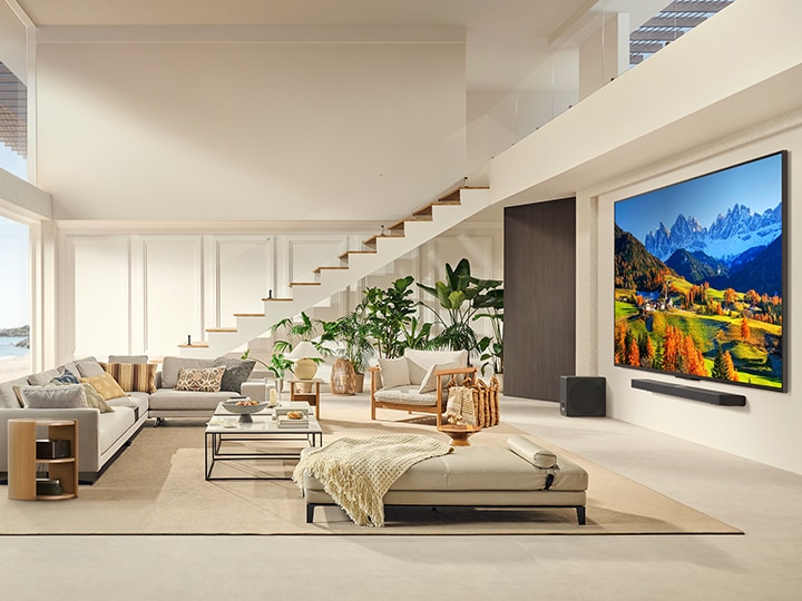 LG QNED TV, der in einem modernen Wohnraum an einer Wand über einer LG Soundbar montiert ist. Die Zero Connect Box befindet sich in einem Couchtisch.