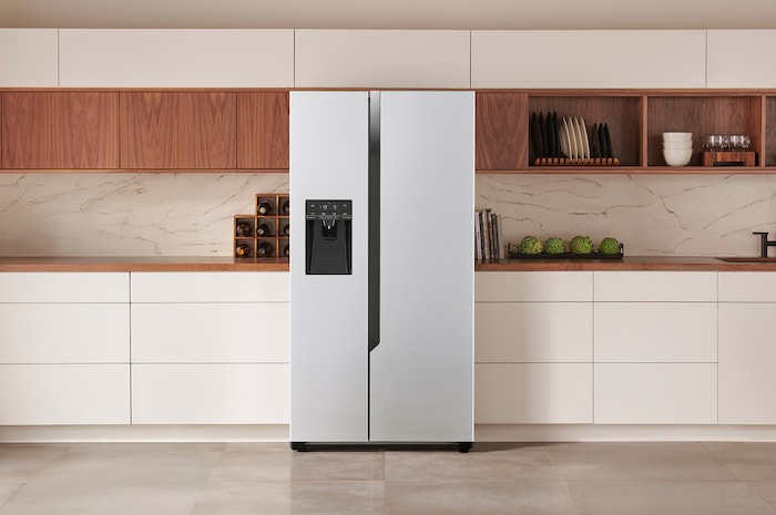 LG Side-by-Side Kühlschrank GSM32HSBEH in Platin-Silber-Optik, elegant in eine moderne Küche mit weißen und holzfarbenen Schränken und integriertem Wasserspender integriert.