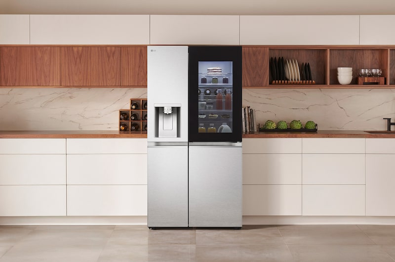LG Side-by-Side Kühlschrank GSXE91MBAD in Edelstahl-Optik mit InstaView™ Door-in-Door® und Wasserspender, elegant in eine moderne Küche mit weißer und hölzerner Arbeitsplatte integriert.