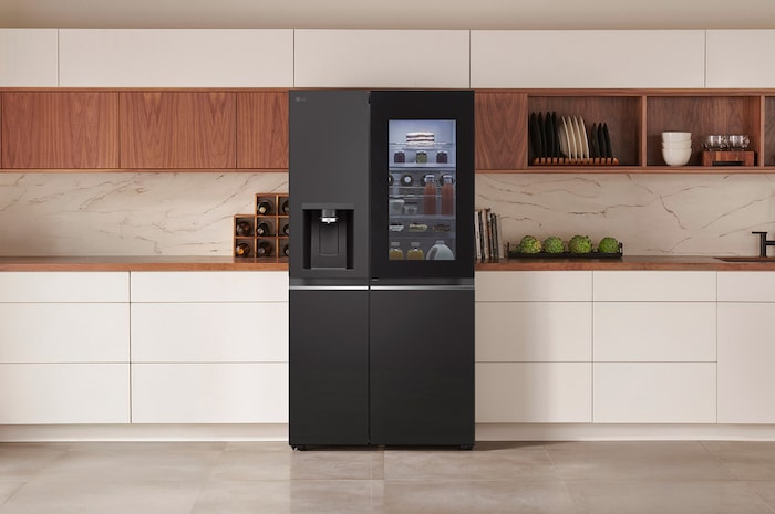 LG Side-by-Side Kühlschrank GSXE81EVBD in mattem Schwarzstahl mit InstaView™ Door-in-Door® und Wasserspender, elegant in eine moderne Küche mit weißer und hölzerner Arbeitsplatte integriert.