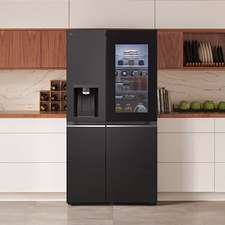 LG Side-by-Side Kühlschrank GSXE81EVBD in mattem Schwarzstahl mit InstaView™ Door-in-Door® und Wasserspender, elegant in eine moderne Küche mit weißer und hölzerner Arbeitsplatte integriert.