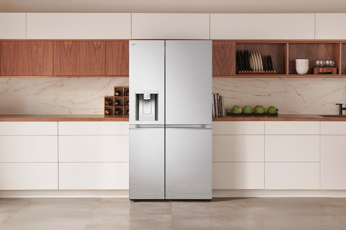 LG Side-by-Side Kühlschrank GSLE91MBAC in Edelstahl-Optik, elegant integriert in eine moderne Küche mit weißer und hölzerner Arbeitsplatte und integriertem Wasserspender.