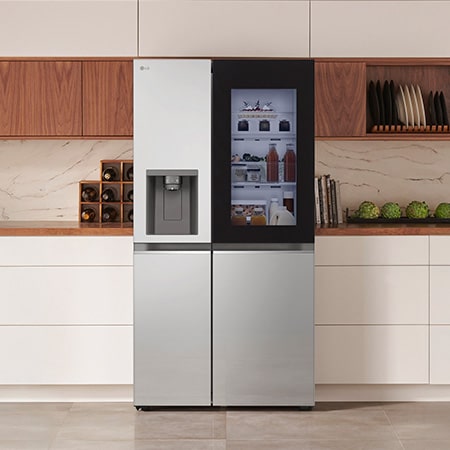 LG Side-by-Side Kühlschrank GSGV81PYLL in Edelstahl-Optik mit InstaView™ Door-in-Door® und Wasserspender, elegant in eine moderne Küche mit weißer und hölzerner Arbeitsplatte integriert.
