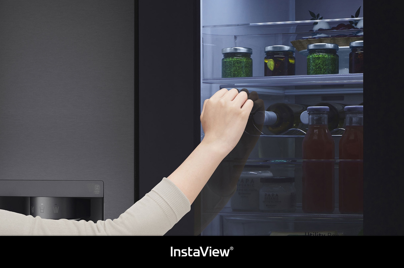 LG Side-by-Side GSXV90MCAE zeigt **InstaView** Door-in-Door: Eine Hand greift nach einer Flasche durch die halb geöffnete Innentür, wobei das beleuchtete Fach sichtbar ist.