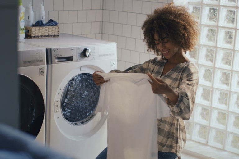 Eine Frau freut sich im Wäscheraum über saubere Kleidung