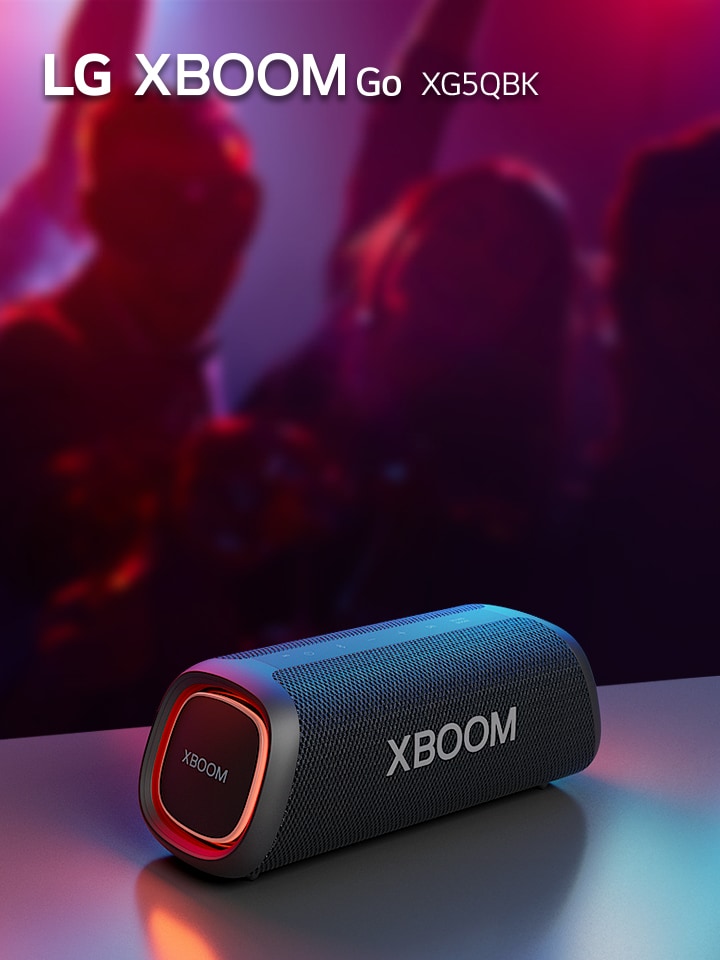 Der orangefarben beleuchtete LG XBOOM Go XG5 steht auf einem Metalltisch. Im Hintergrund genießt eine Menschengruppe die Musik.