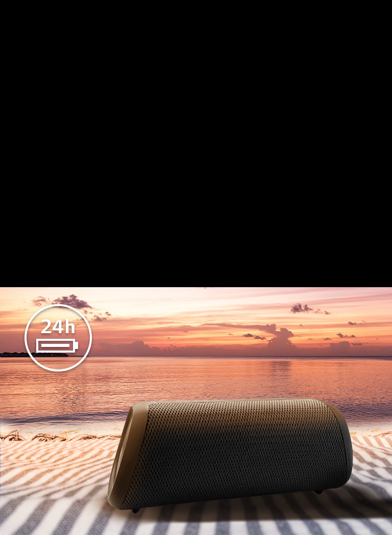 Der Lautsprecher befindet sich auf einem Strandtuch. Im Hintergrund ist ein Sonnenuntergang zu sehen, um zu verdeutlichen, dass das Gerät bis zu 24 Stunden lang betrieben werden kann.