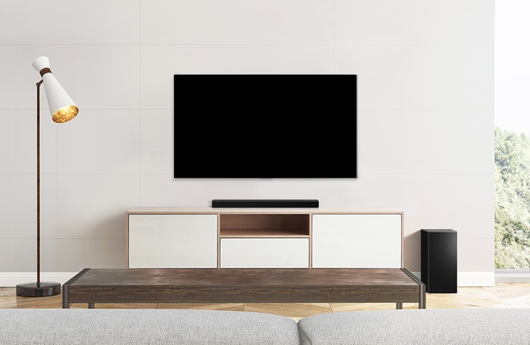Ein TV, eine Soundbar und ein Subwoofer in einem schlicht eingerichteten Wohnzimmer.