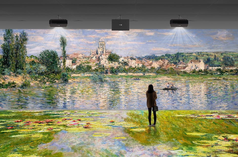 Ein an der Museumsdecke montierter Projektor zeigt ein Kunstwerk und eine Frau beobachtet es.	