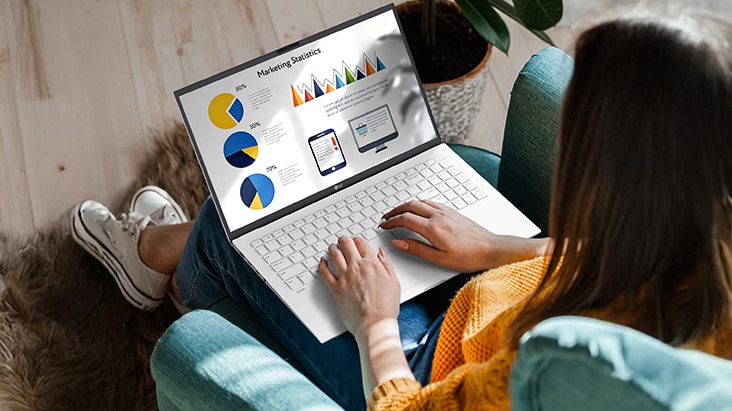 Eine Person sitzt bequem auf einem Stuhl und verwendet einen Laptop, auf dem eine Präsentation mit Diagrammen und Grafiken angezeigt wird. Eine Animation veranschaulicht den blendfreien Bildschirm, indem sie zeigt, dass selbst bei direkter Sonneneinstrahlung keine Lichtreflexion auftritt.