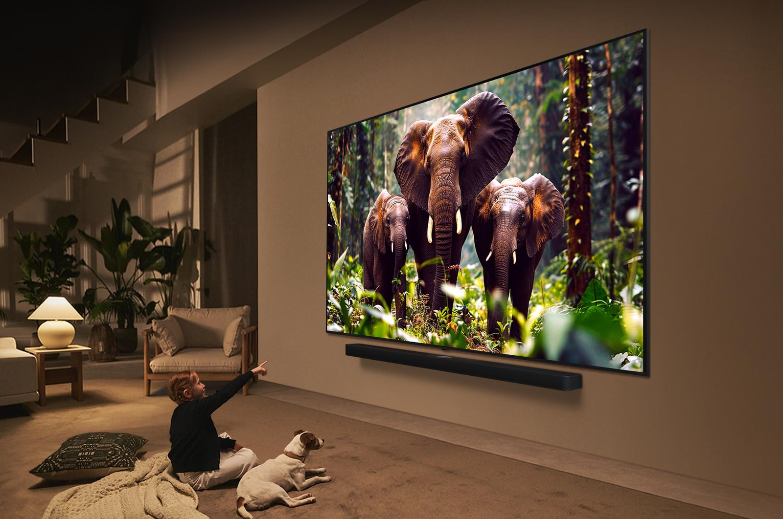 Ein Mädchen und ein Hund sitzen vor einem LG QNED-Fernseher, der an einer Wand montiert ist und drei Elefanten zeigt, die über einer LG Soundbar nach außen laufen. Der Titel spricht davon, dass jede Aktion auf einem großen Bildschirm noch spannender ist.