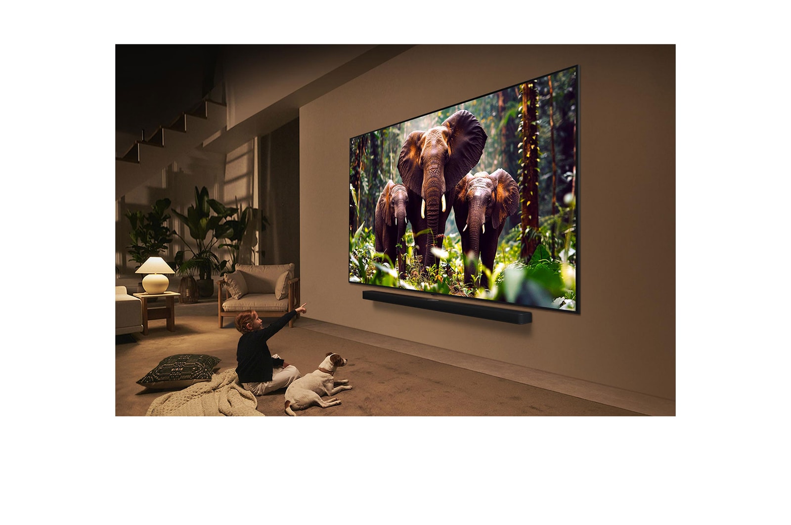 Ein Mädchen und ein Hund sitzen vor einem LG QNED-Fernseher, der an einer Wand montiert ist und drei Elefanten zeigt, die über einer LG Soundbar nach außen laufen. Der Titel spricht davon, dass jede Aktion auf einem großen Bildschirm noch spannender ist.
