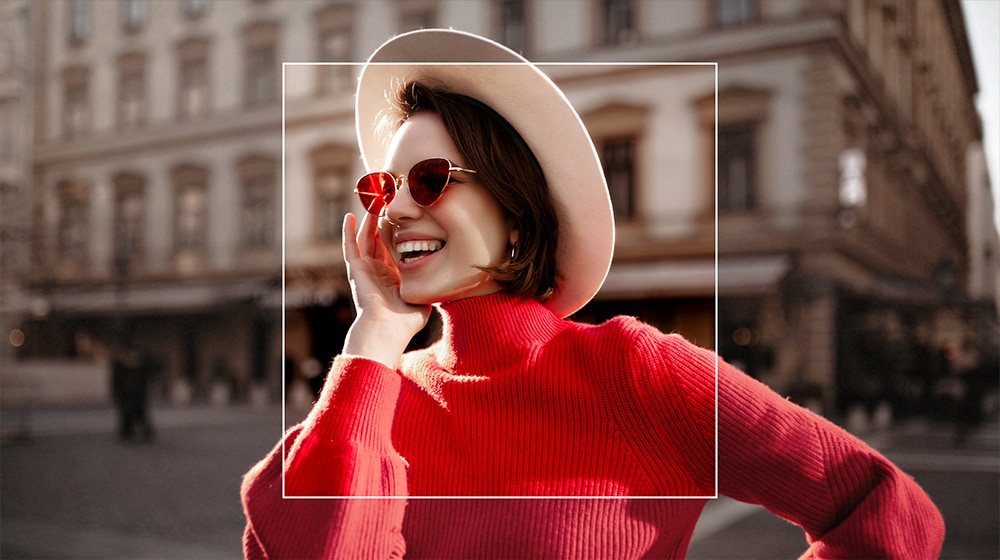 Ein Bild einer Frau in einer Stadt. Ein Quadrat wird über die Frau gelegt, was ein AI Super Upscaling darstellt. So wird sie vor einem kunstvoll unscharfen Hintergrund mit Detail in den Fokus gestellt.