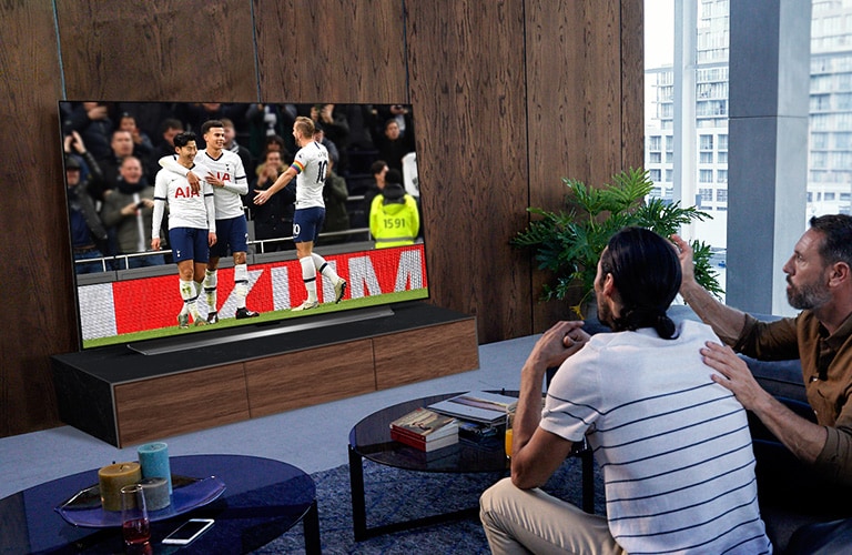Personen, die sich ein Spiel von "Tottenham" in ihrem Wohnzimmer auf dem Fernseher ansehen