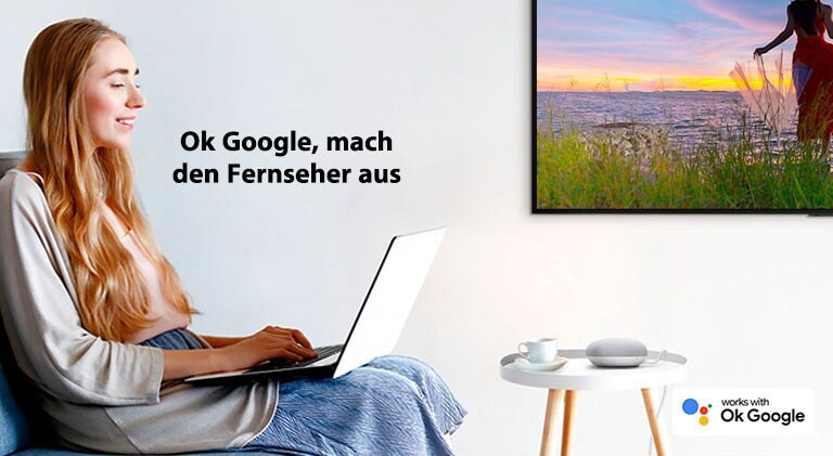Eine Frau mit einem Laptop sitzt auf einer Couch in einem Raum mit einem Fernseher an der Wand und befiehlt einem Smart Speaker, den Fernseher auszuschalten.
