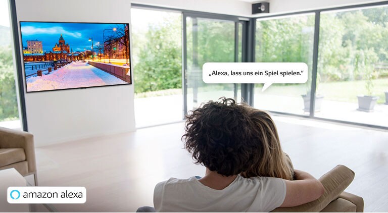 Ein Paar sitzt auf dem Sofa und bittet Amazon Alexa, ein Spiel anzuzeigen.