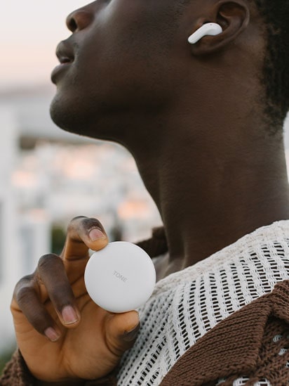 Image of a man with ToneFree on his Ear. Grapping ToneFree in his hand.