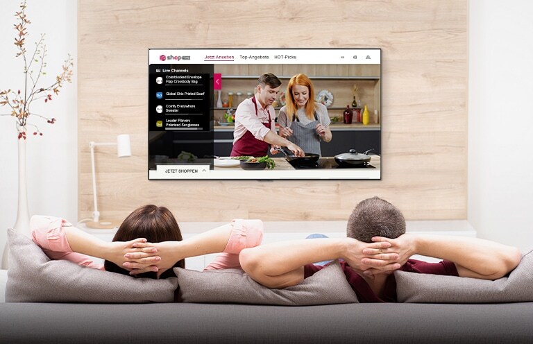 The image of a man and a woman sitting on a sofa watching a shop live.