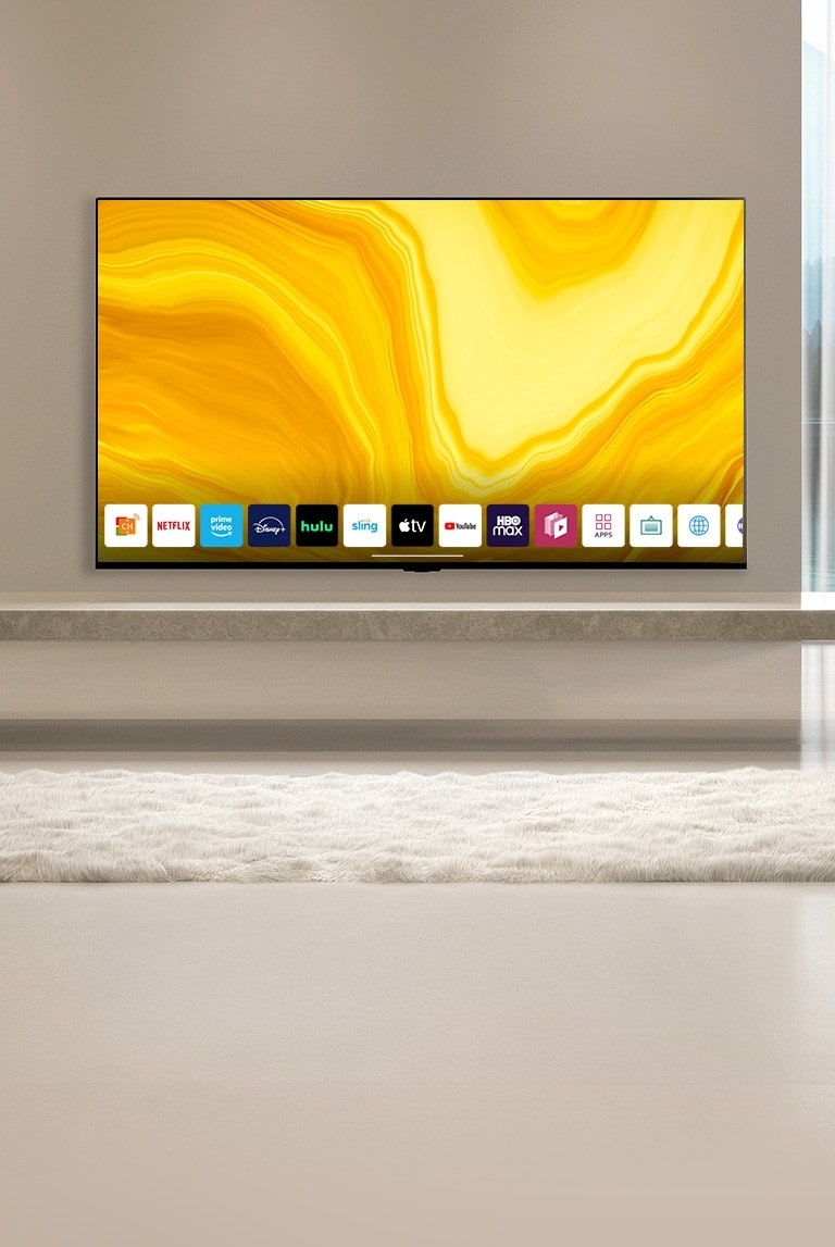 Auf dem Startbildschirm wird nach unten gescrollt und die Szene wechselt zu einem Fernseher, der in einem in warmen Farben eingerichteten Wohnzimmer hängt und den Startbildschirm anzeigt. 